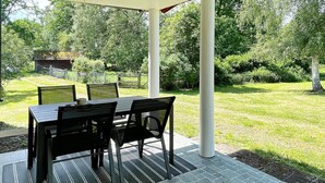 An outdoor patio with a table and chairs, surrounded by a brick floor and a grassy area with trees. - 7 Person Holiday Home in Hogsby (Högsby)