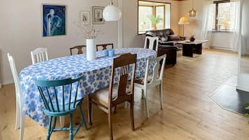 Ein Essbereich mit einem runden Tisch, der mit einer blau-blumigen Tischdecke bedeckt ist, umgeben von Holzsesseln.