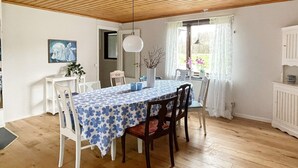 A dining area with a table set for four, wooden flooring, white walls, and a ceiling with wooden beams. - 7 Person Holiday Home in Hogsby (Högsby)