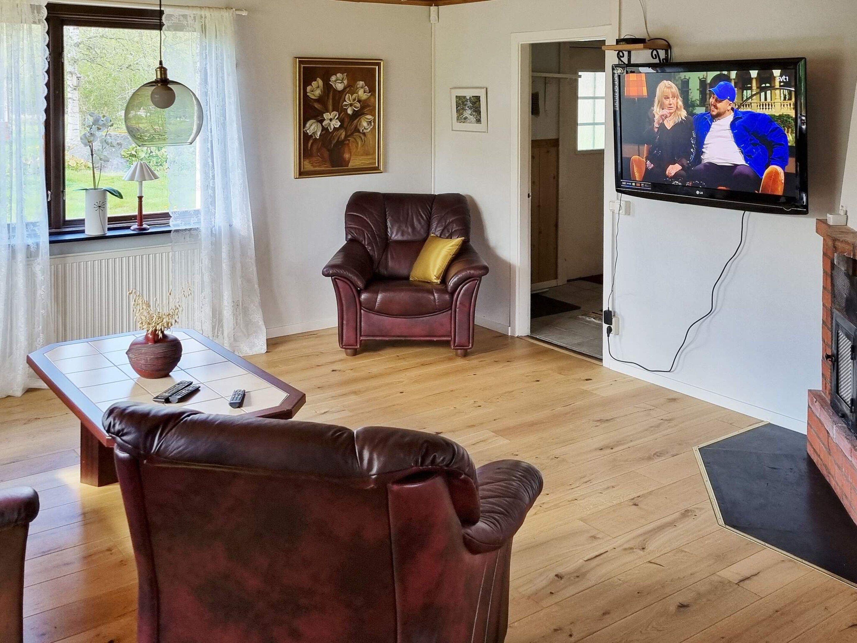 Un salon avec un fauteuil en cuir, un téléviseur et une cheminée.