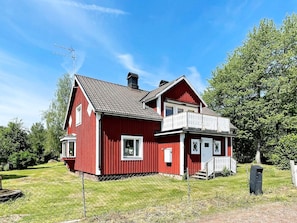 A red two-story house with a balcony, a chimney, and a fenced yard. - 7 Person Holiday Home in Hogsby (Högsby)