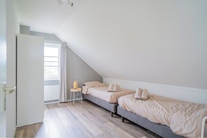 Un dormitorio con dos camas, un radiador, una ventana con cortinas y una puerta.