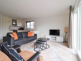Ein modernes Wohnzimmer mit einer Couch, einem Couchtisch und einem Fernseher.