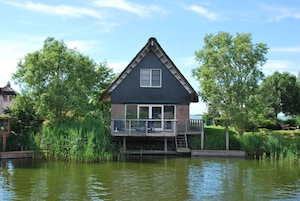 Ein Haus mit Balkon, Fenster und einem Teich davor.