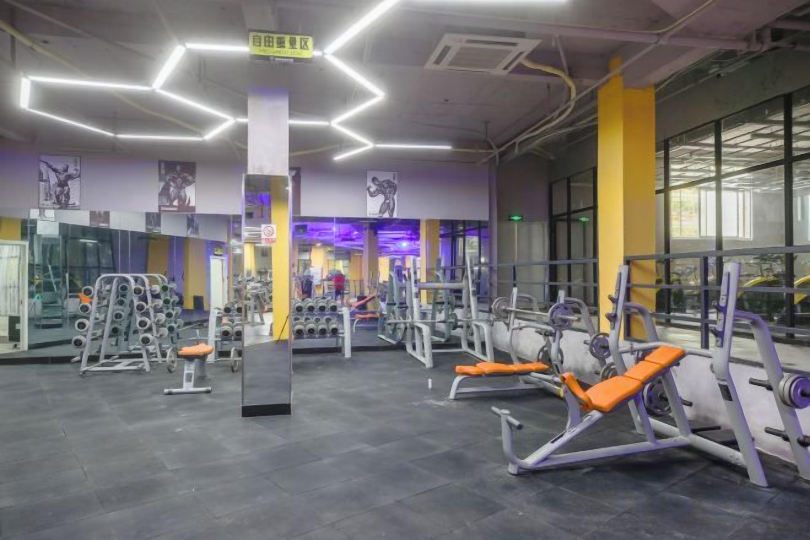 Un gimnasio con diversos equipos de ejercicio, espejos y un diseño de techo moderno.