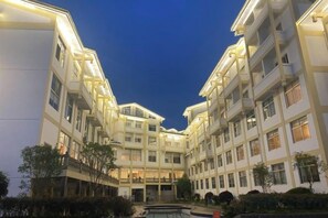 Un hôtel à plusieurs étages doté d’une cour intérieure, de balcons et d’une façade bien éclairée.