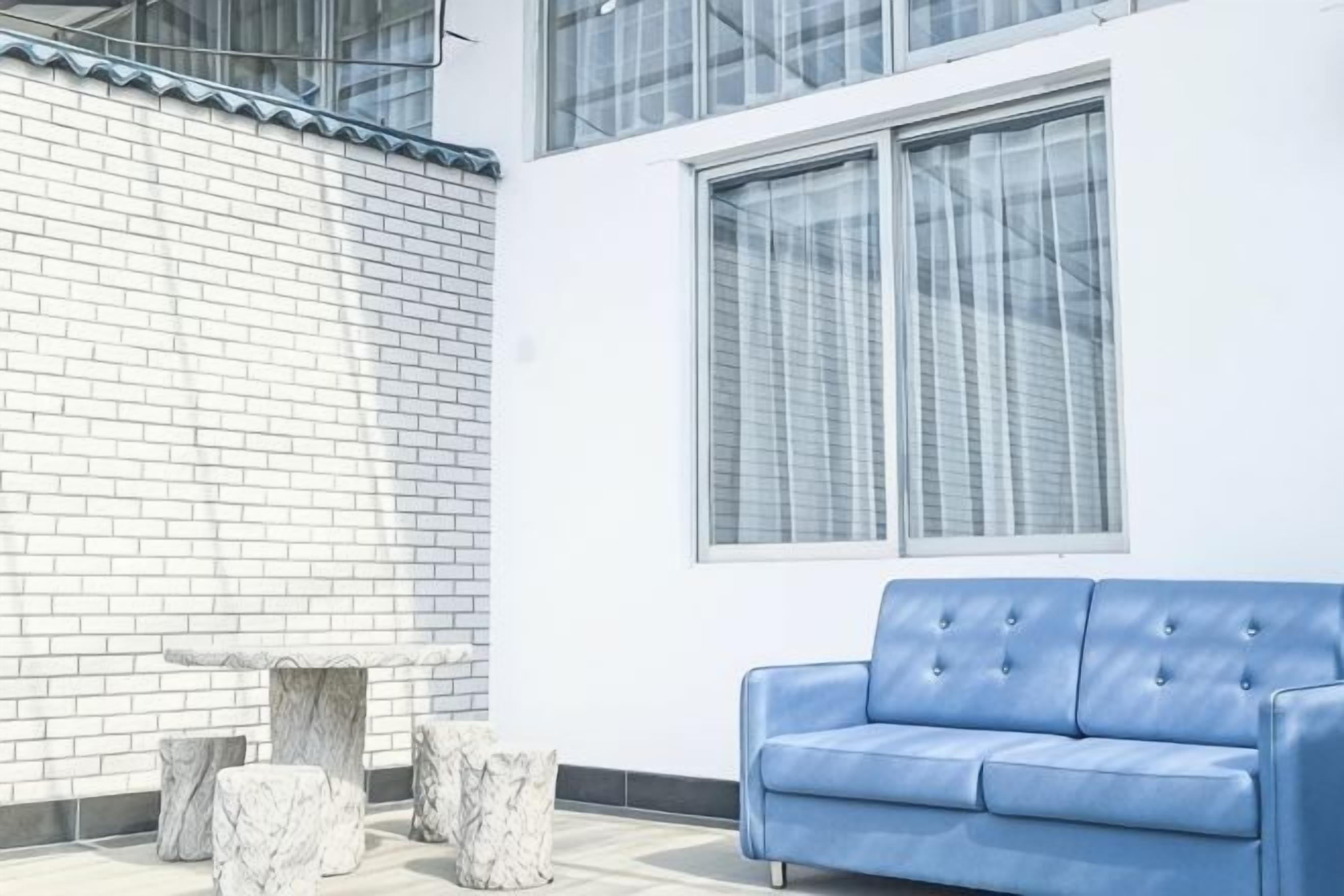 A modern room with a white brick wall, a blue sofa, and a marble table.