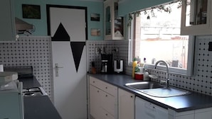 Eine kompakte Küche mit schwarz-weiß gefliestem Boden, einem Spülbecken und einem Fenster mit Blick nach draußen.