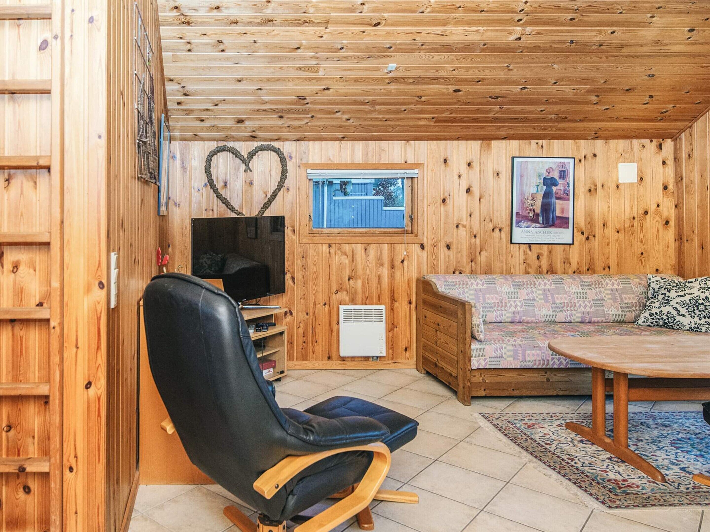 Een gezellig cabinteer met een houten plafond, een televisie, een bank en een eettafel.