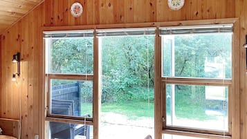 A wooden interior with large windows, a dining table, and chairs.
