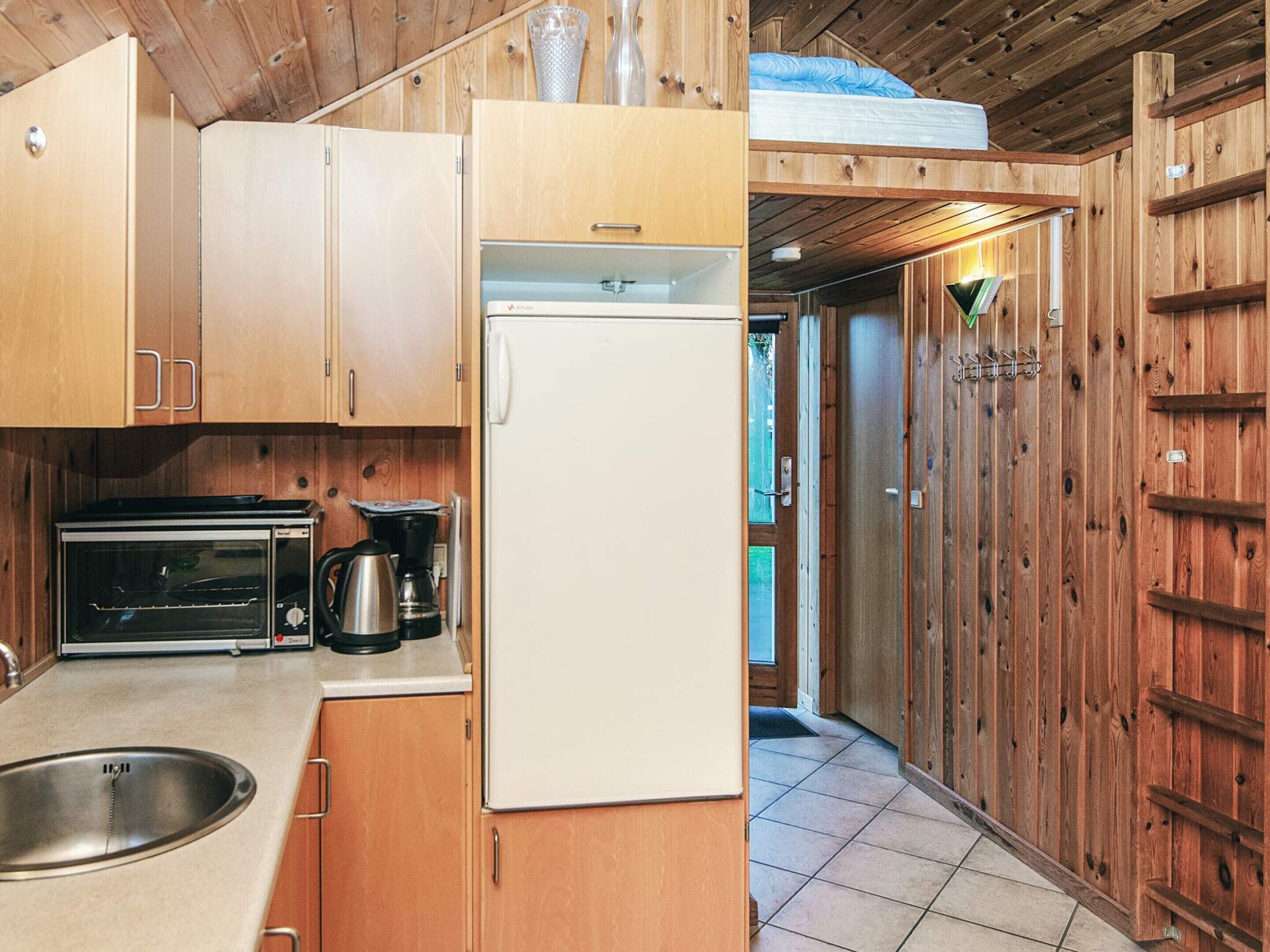 A compact kitchen with wooden cabinets, a white refrigerator, a toaster, and a coffee maker.