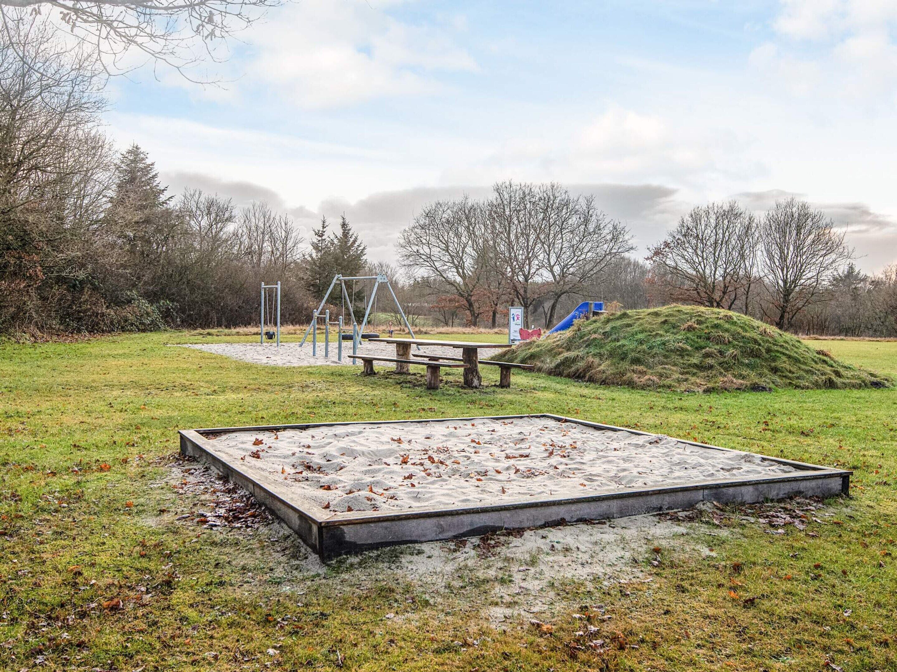 A playground with swings, a slide, and a sandbox.