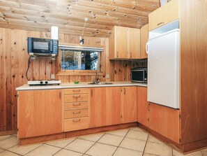 Una cocina funcional con armarios de madera, un microondas, una estufa y un refrigerador.