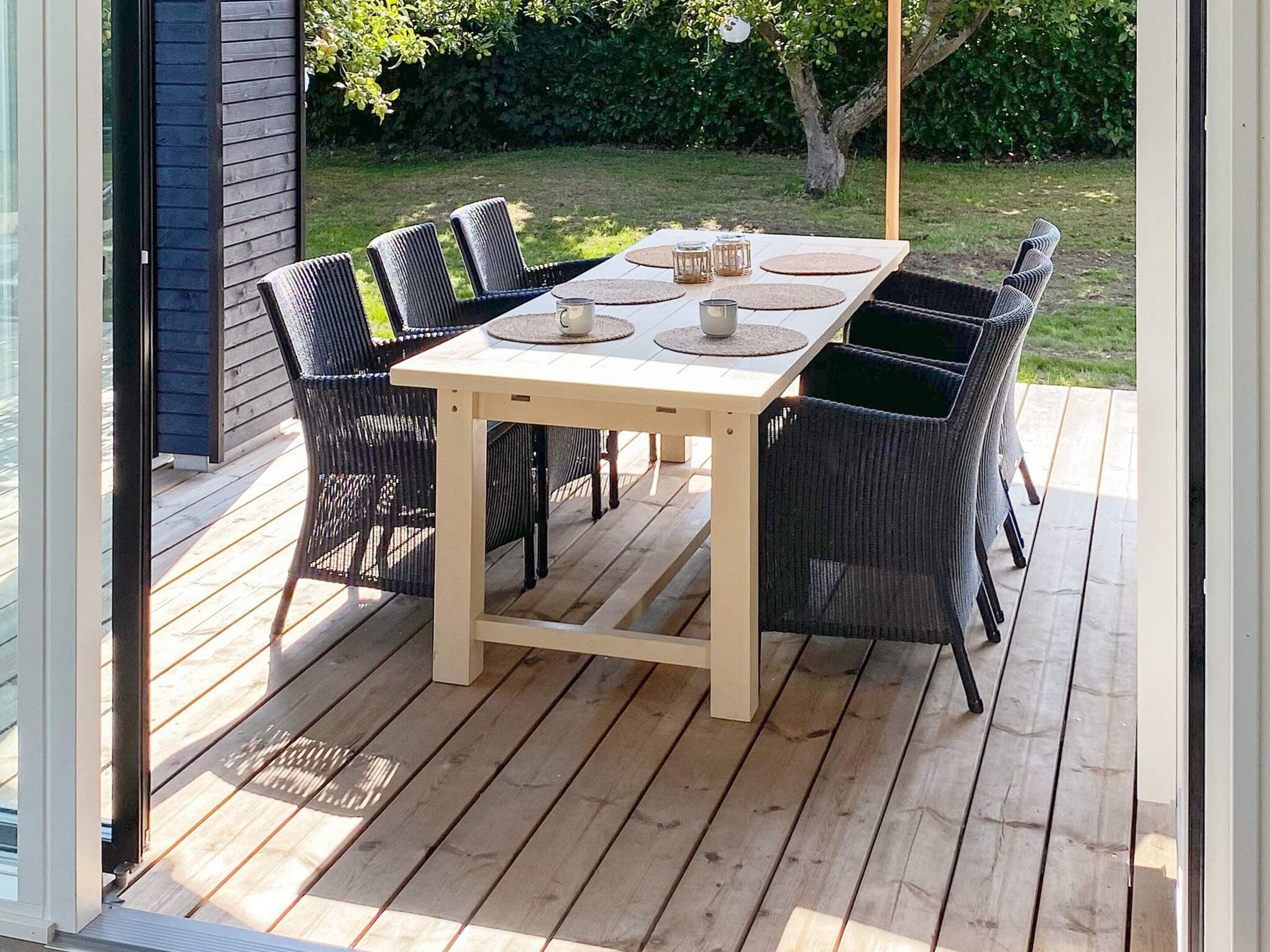 Une terrasse extérieure avec une table en bois et six chaises en osier.