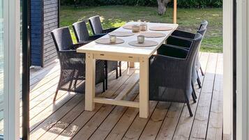 An outdoor patio with a wooden table and six wicker chairs.