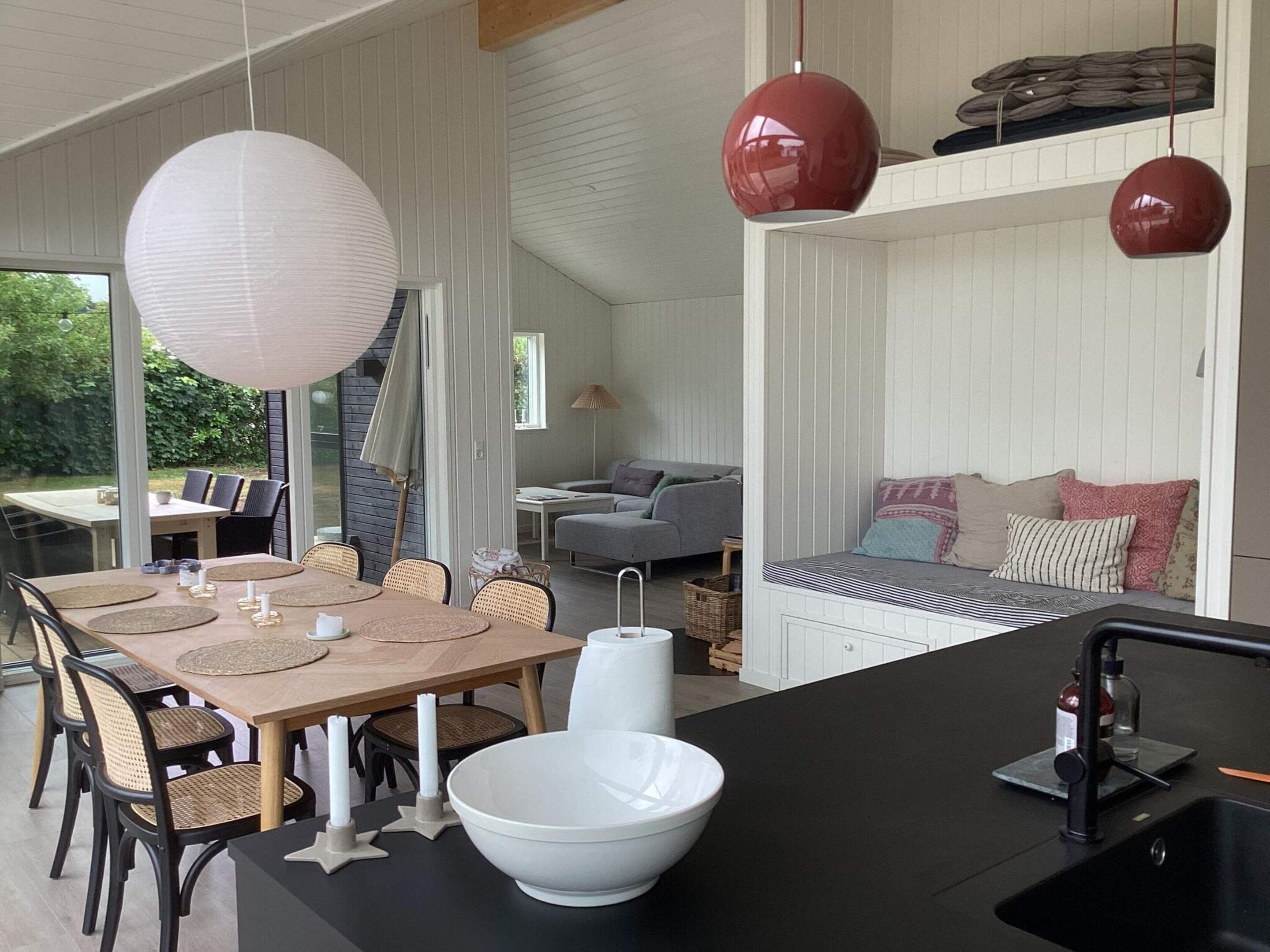 A modern kitchen with a central island, dining area with chairs, and a sofa.
