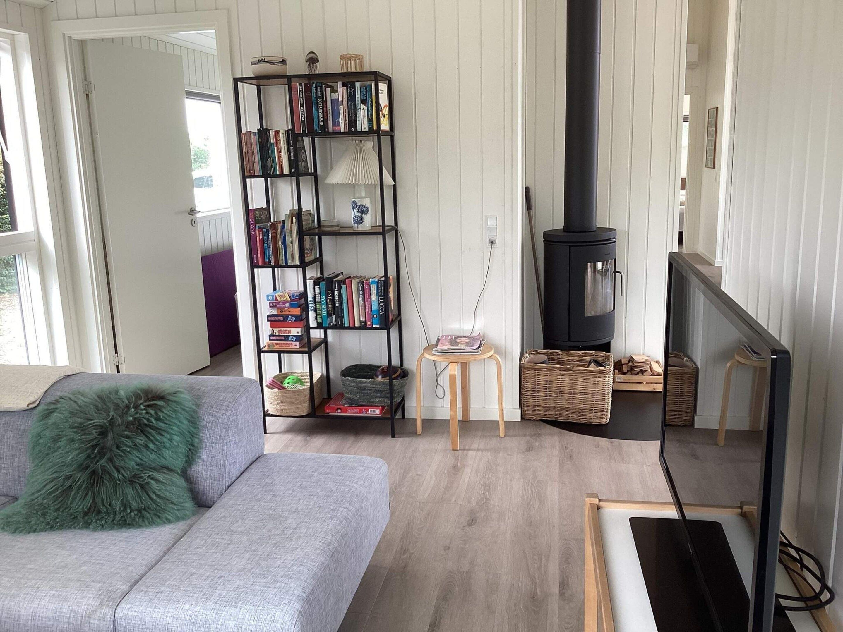 A living room with a grey sofa, a black bookshelf, a fireplace, and a television.