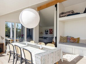 A dining area with a table and chairs, a hanging light fixture, and a view of the outdoors. - 4 Star Holiday Home in Juelsminde (Juelsminde)
