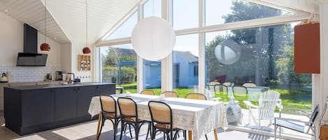 Una cocina moderna con comedor, ventanas amplias y vistas al exterior.