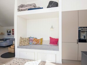 Ett kompakt bostadsutrymme med en inbyggd bänk, ett litet kök och en soffa.