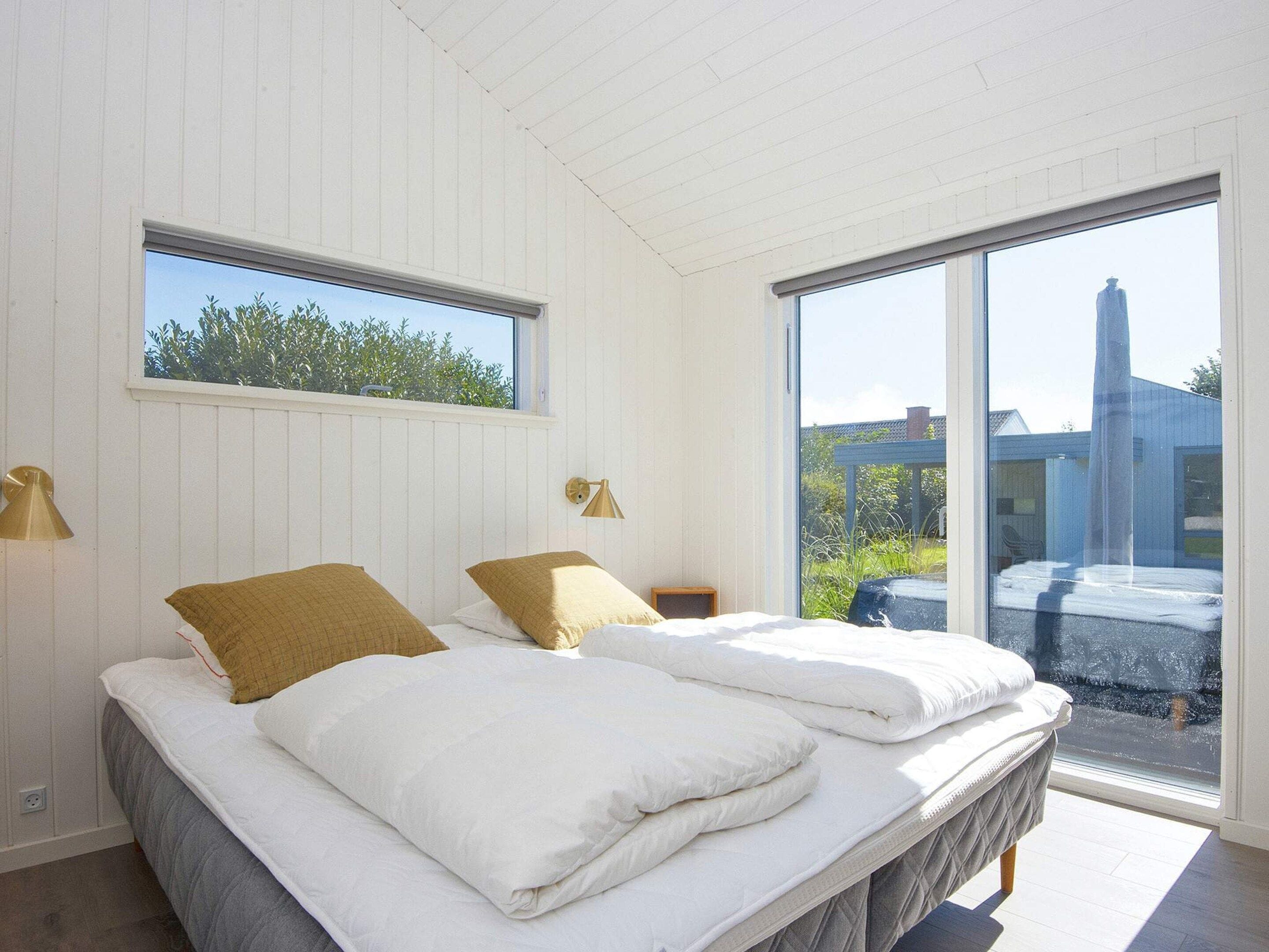 A bedroom with two beds, a large window, and a view of the outside.