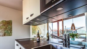Eine moderne Küche mit Spüle aus Edelstahl, weißen Schränken und einem großen Fenster mit Blick auf Gebäude und Berge.