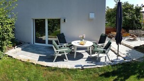 A patio with a table and chairs, a small garden, and a swing set.