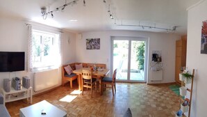 A living room with a TV, sofa, and dining area with chairs and a table.