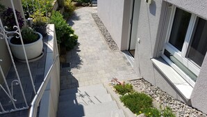 A narrow pathway leading to a modern building with a glass door and a window.