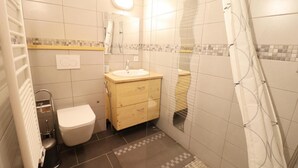 Pieni kylpyhuone, jossa on wc, pesuallas ja suihku.