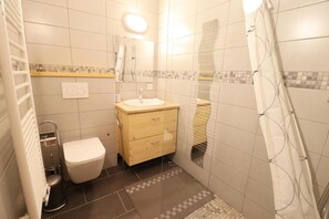Une petite salle de bain comprenant des toilettes, un lavabo et une douche.
