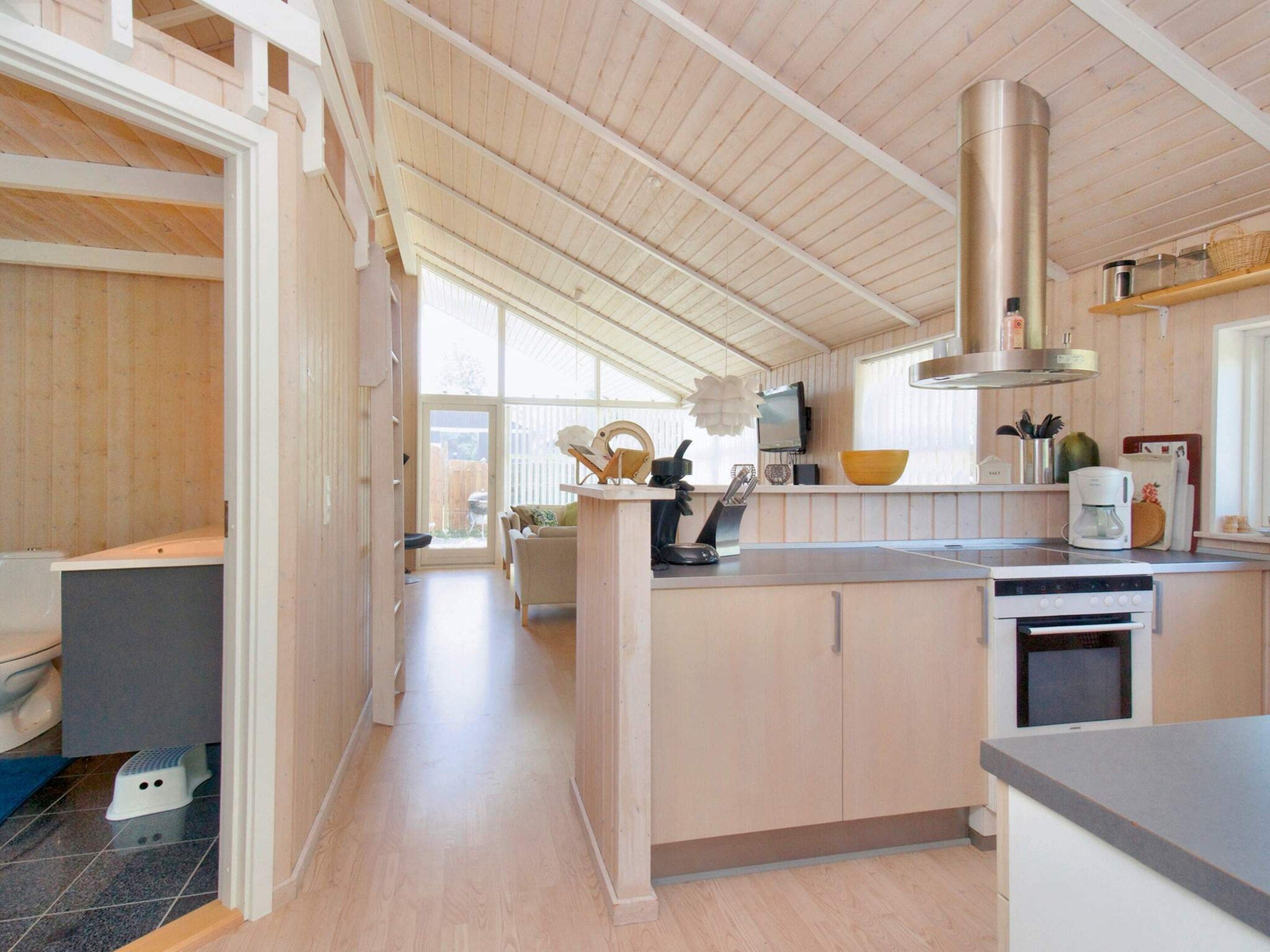 A modern kitchen with wooden cabinetry, a stainless steel range hood, and a built-in oven.