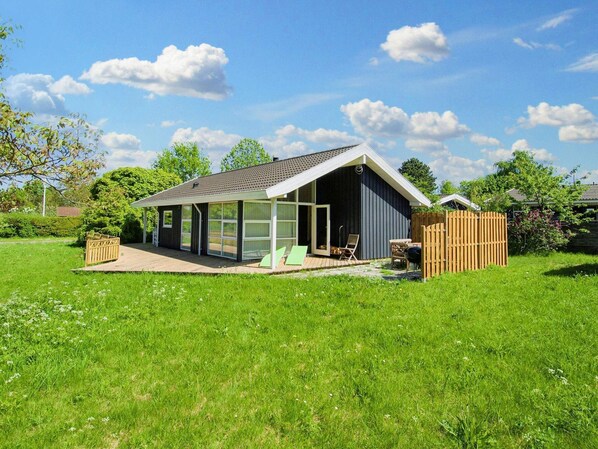 A modern house with a large glass extension, a patio with outdoor furniture, and a fenced backyard. - 6 Person Holiday Home in Skibby (Skibby)