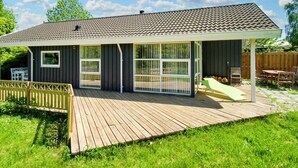 Una casa con un porche cubierto, un patio cercado y una terraza de madera.
