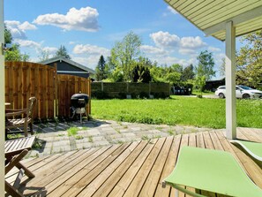 A wooden deck with a barbecue grill, a covered patio area, and a fenced backyard. - 6 Person Holiday Home in Skibby (Skibby)