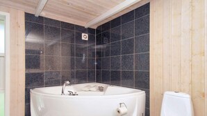 Un baño con una bañera independiente, un inodoro y un cabezal de ducha.