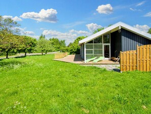 A modern house with a covered patio, a wooden fence, and a lawn. - 6 Person Holiday Home in Skibby (Skibby)