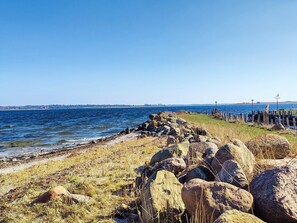 Paisatge costaner amb una riba rocosa, una zona verda i una vista clara del mar.