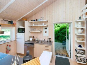 A compact kitchen with a refrigerator, microwave, and sink. There are shelves above the counter holding various kitchenware. - 6 Person Holiday Home in Skibby (Skibby)