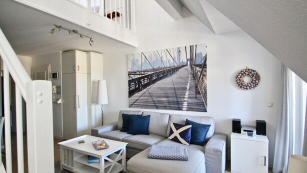 A modern living room with a sofa, coffee table, and a painting of a bridge. - Nice Apartment With Wifi (Kuehlungsborn)