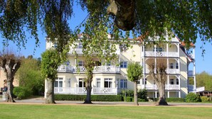 A multi-story hotel with a white facade, balconies, and a well-maintained lawn. - Nice Apartment With Wifi (Kuehlungsborn)