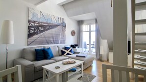 A modern living room with a sofa, coffee table, and a large painting of a bridge. - Nice Apartment With Wifi (Kuehlungsborn)