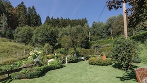 Ein gepflegter Garten mit vielfältigen Pflanzen und einer Statue in der Mitte.