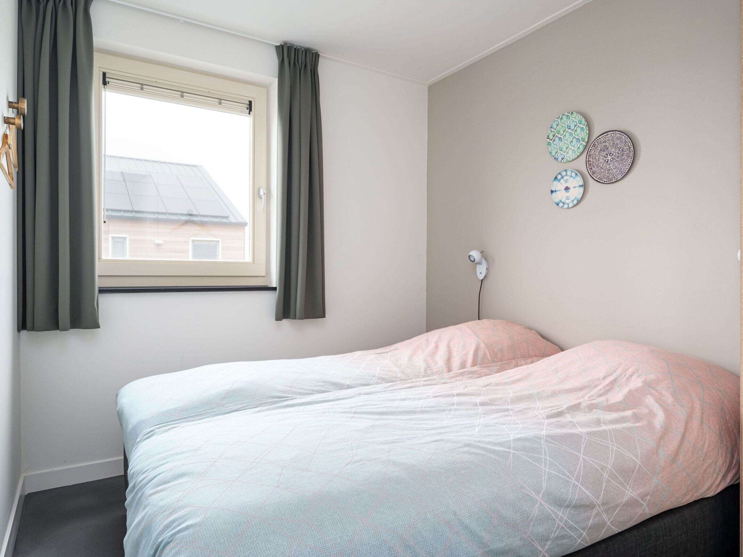 A bedroom with a bed, a window with curtains, and wall decorations.
