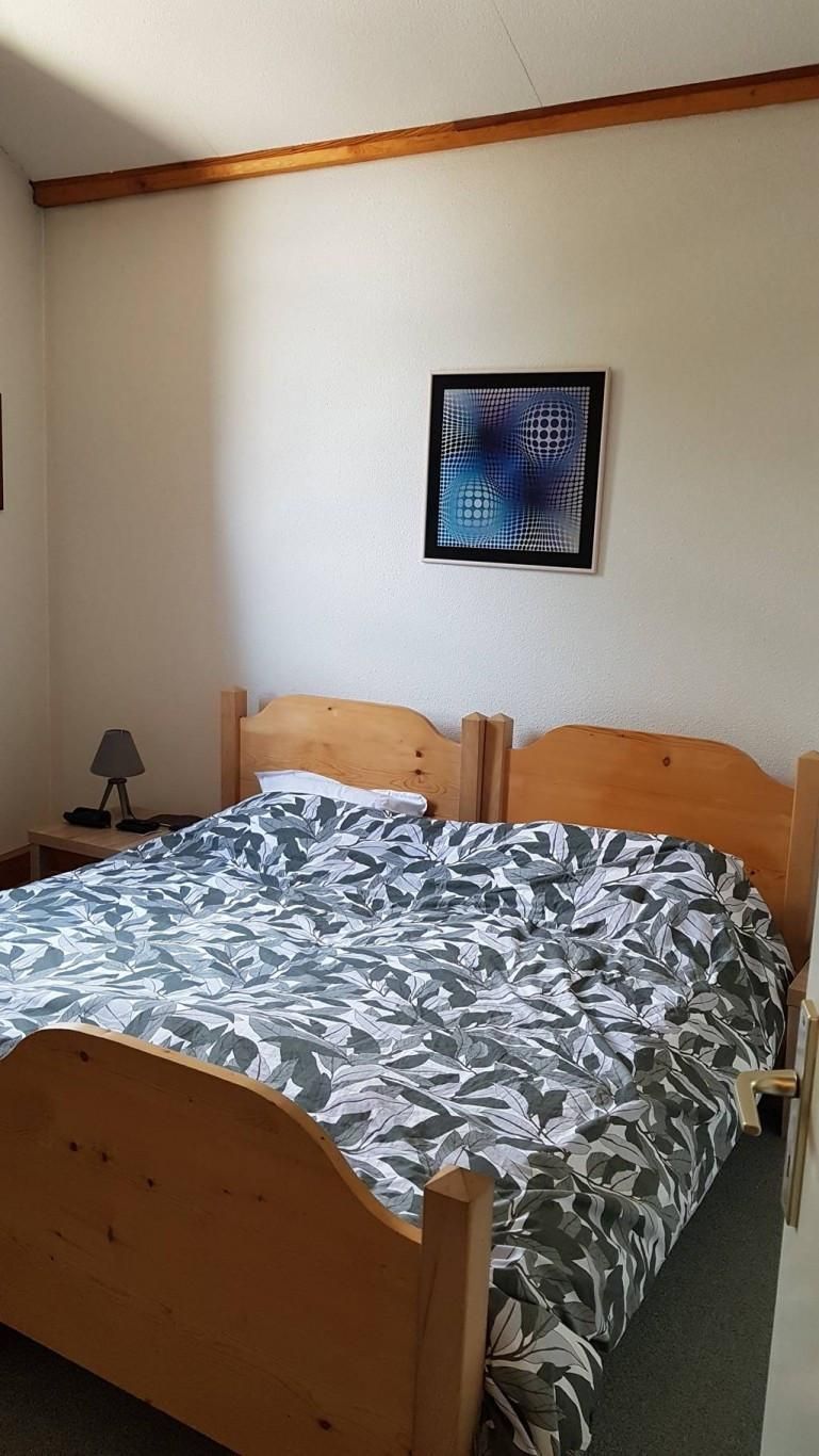 A bedroom with a wooden bed, a nightstand, a lamp, and a framed abstract artwork on the wall.