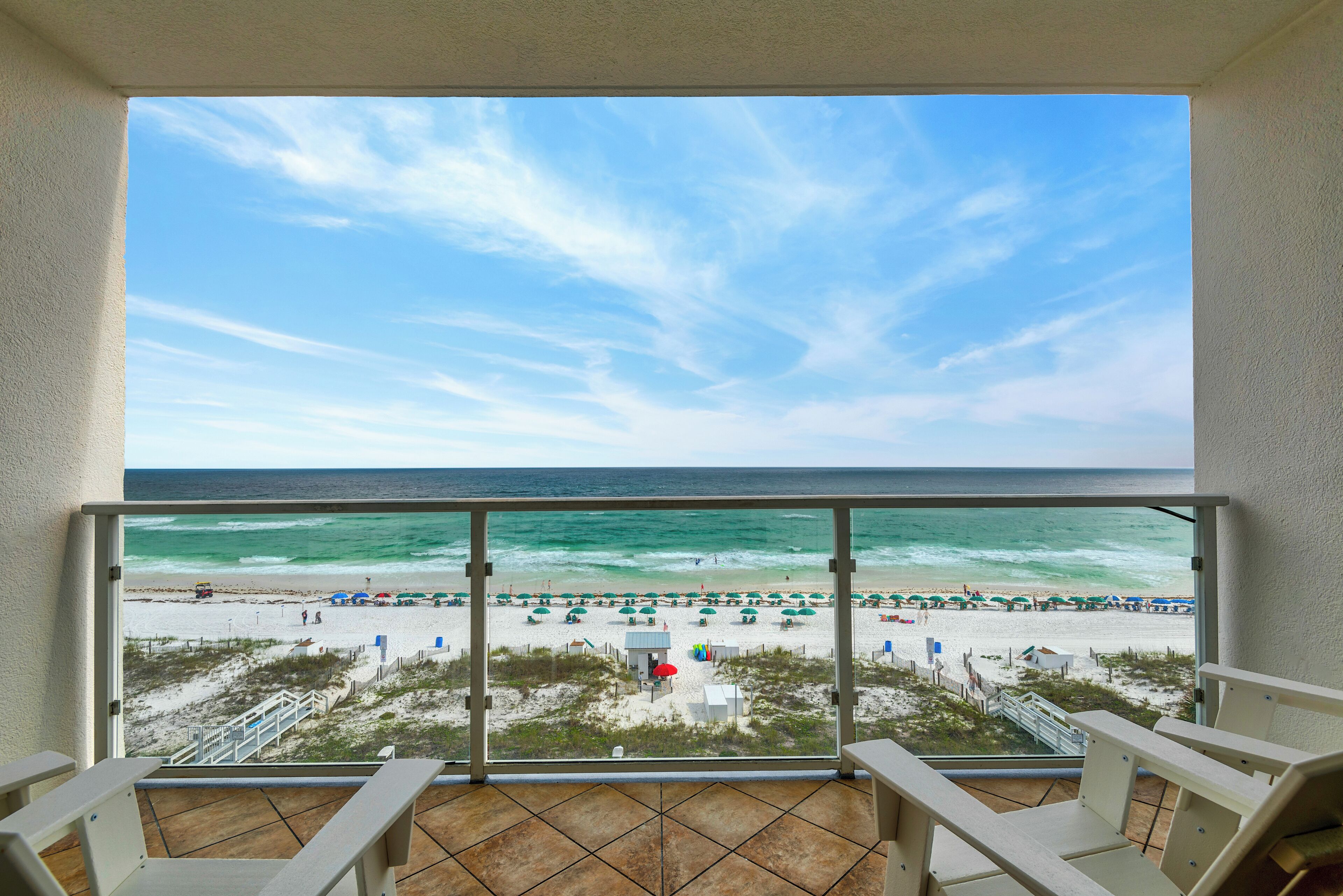 Ein Balkon mit Blick auf einen Strand, inklusive Meer und Strandstühlen.