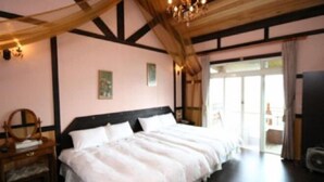 A bedroom with a large bed, wooden beams, a chandelier, and a view of the outdoors. - Xiangqing Garden Leisure Cabin (Nantou)