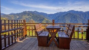 A wooden deck with a table and chairs, overlooking a mountainous landscape. - Xiangqing Garden Leisure Cabin (Nantou)