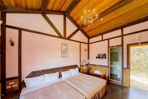 A bedroom with a large bed, wooden beams, a chandelier, a bedside table, and a door leading to a balcony. - Xiangqing Garden Leisure Cabin (Nantou)