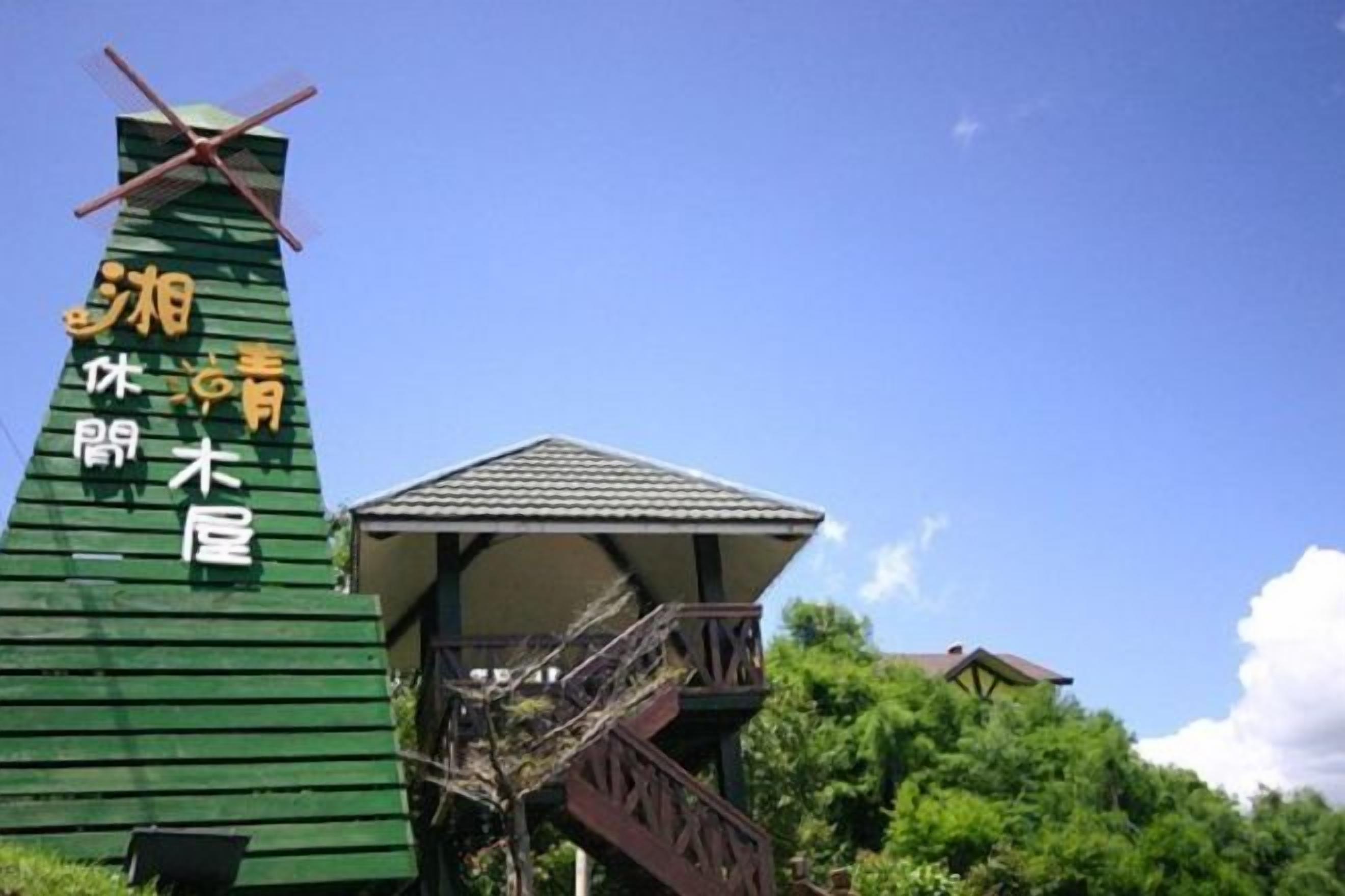 A traditional Japanese windmill with a wooden structure and a small pavilion.